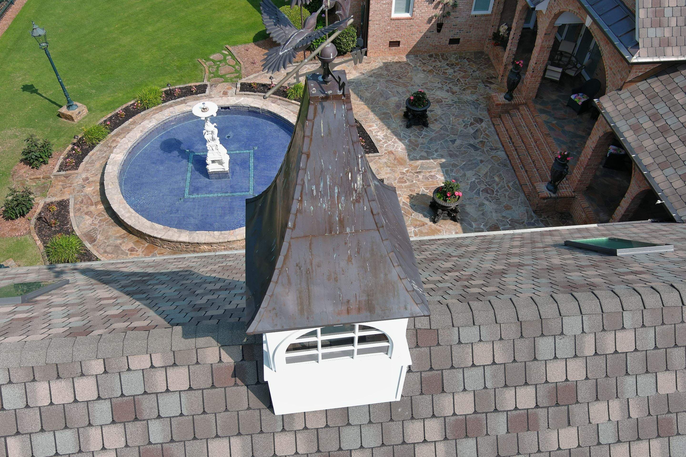Copper-topped cupola and weather vane above a shingle roof